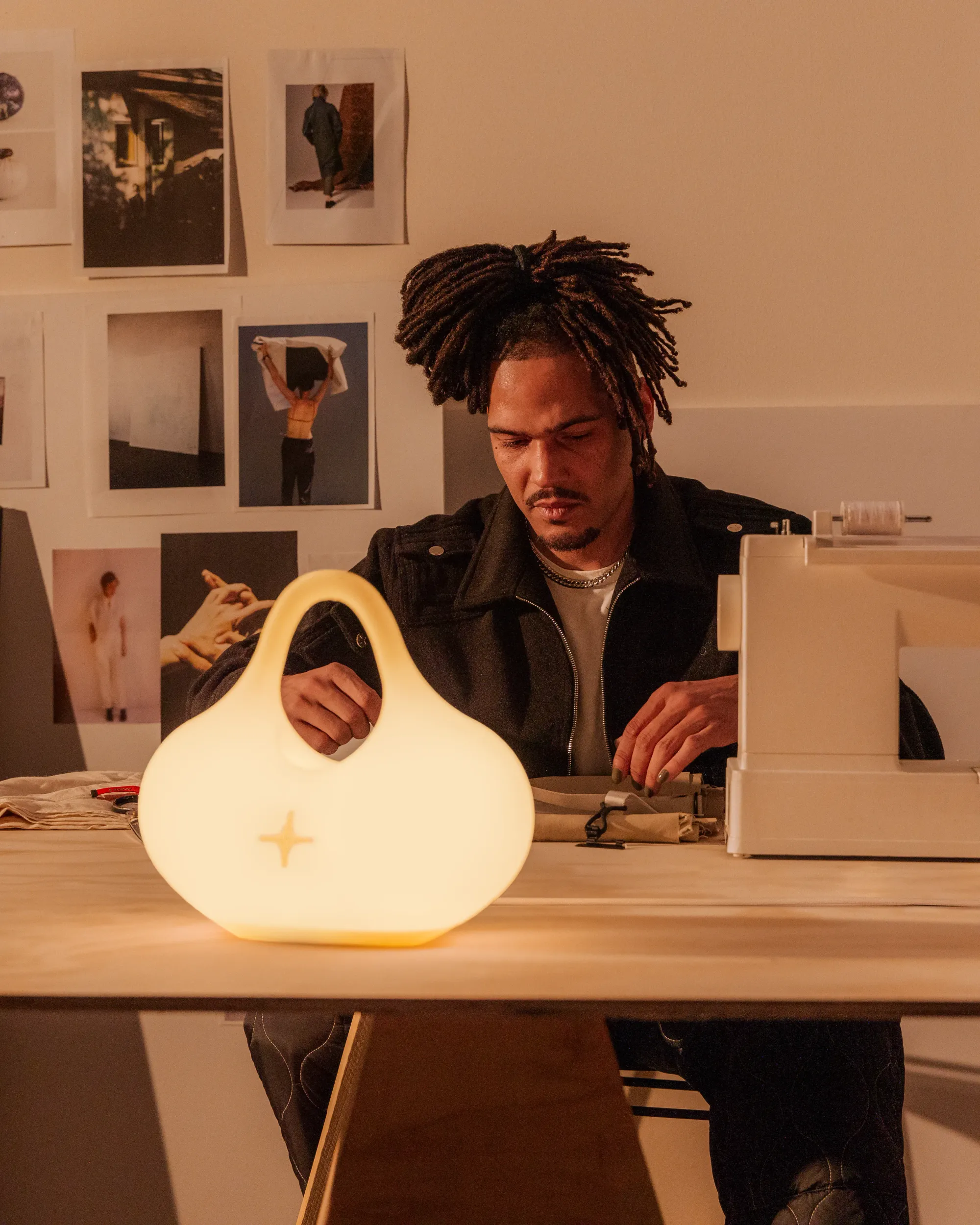 A man is hard at work sewing in their home office table illuminated by Gantri’s Bag Table Light