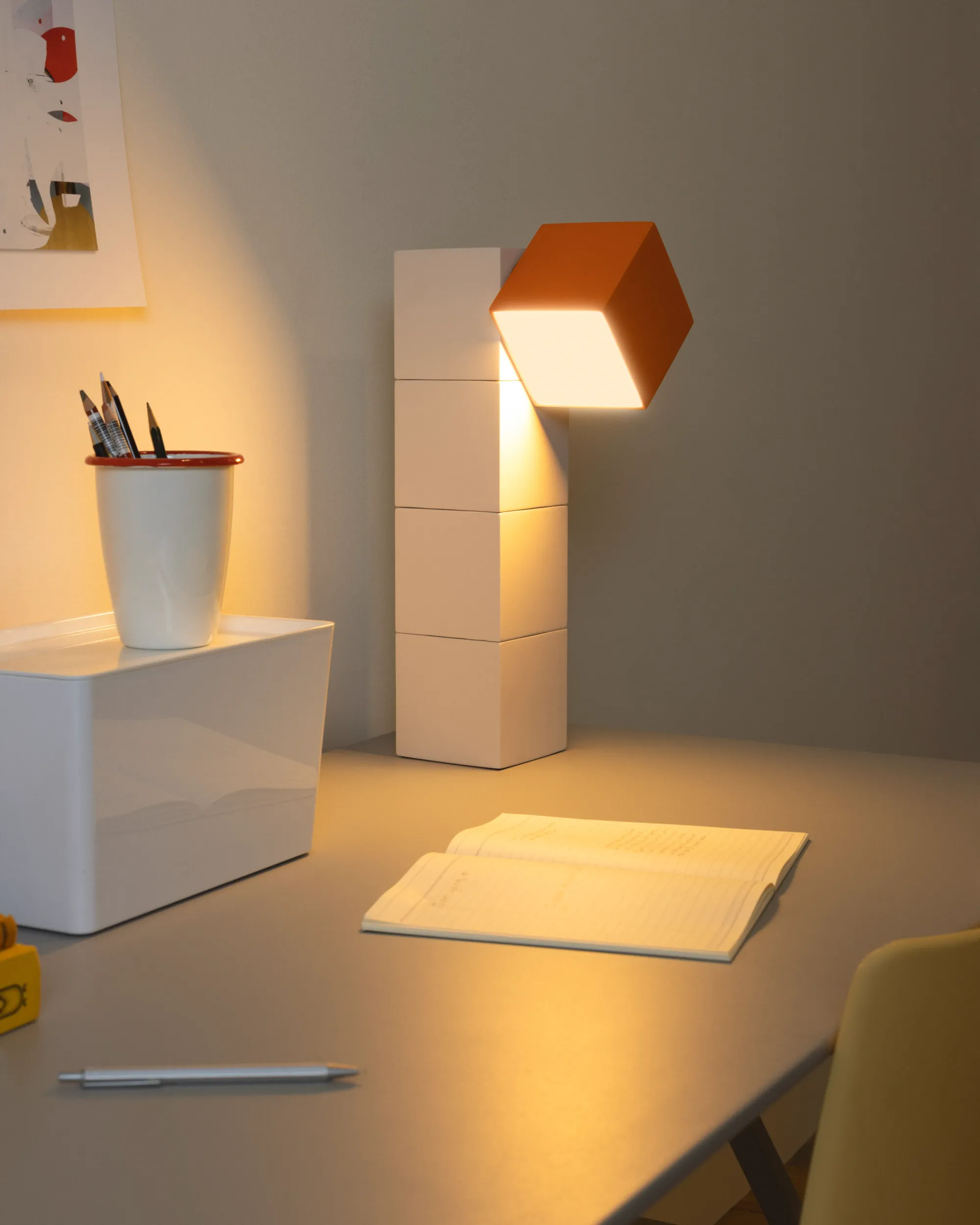 Gantri’s Analog Task Light is illuminating a home office table with an open journal and a penholder filled with pencils