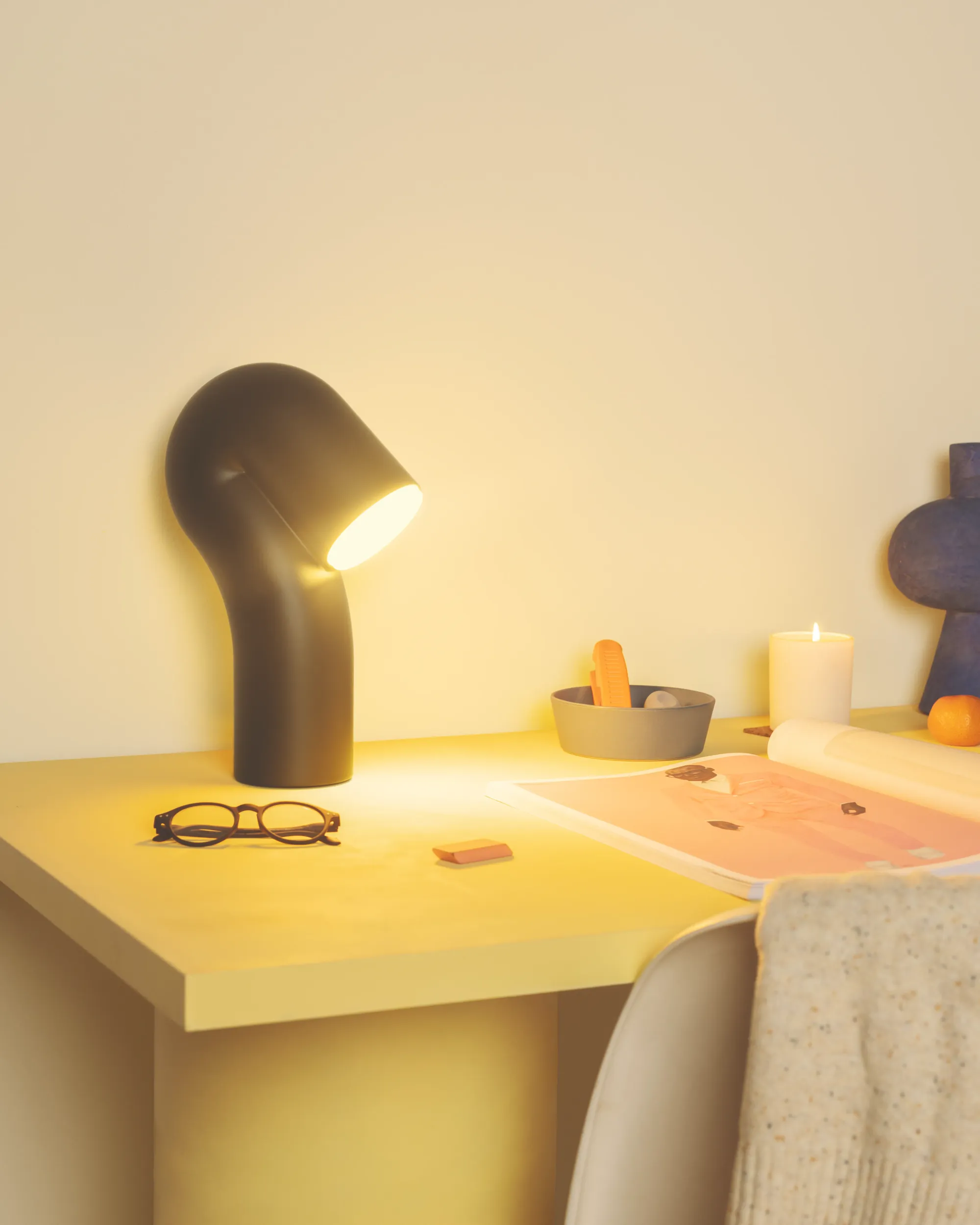 A Smoothy Table Light from Gantri lights up a home office table filled with a pair of glasses and some decorative knick-knacks