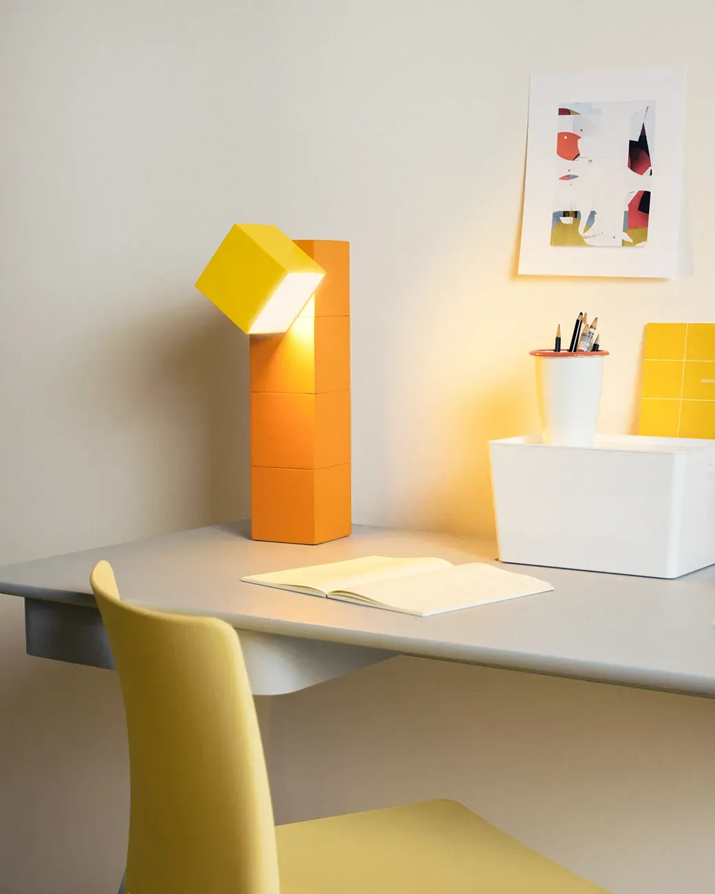 Gantri’s Analog Task Light table lamp is placed on a home office table along with an open blank  journal and a pen holder filled with pencils