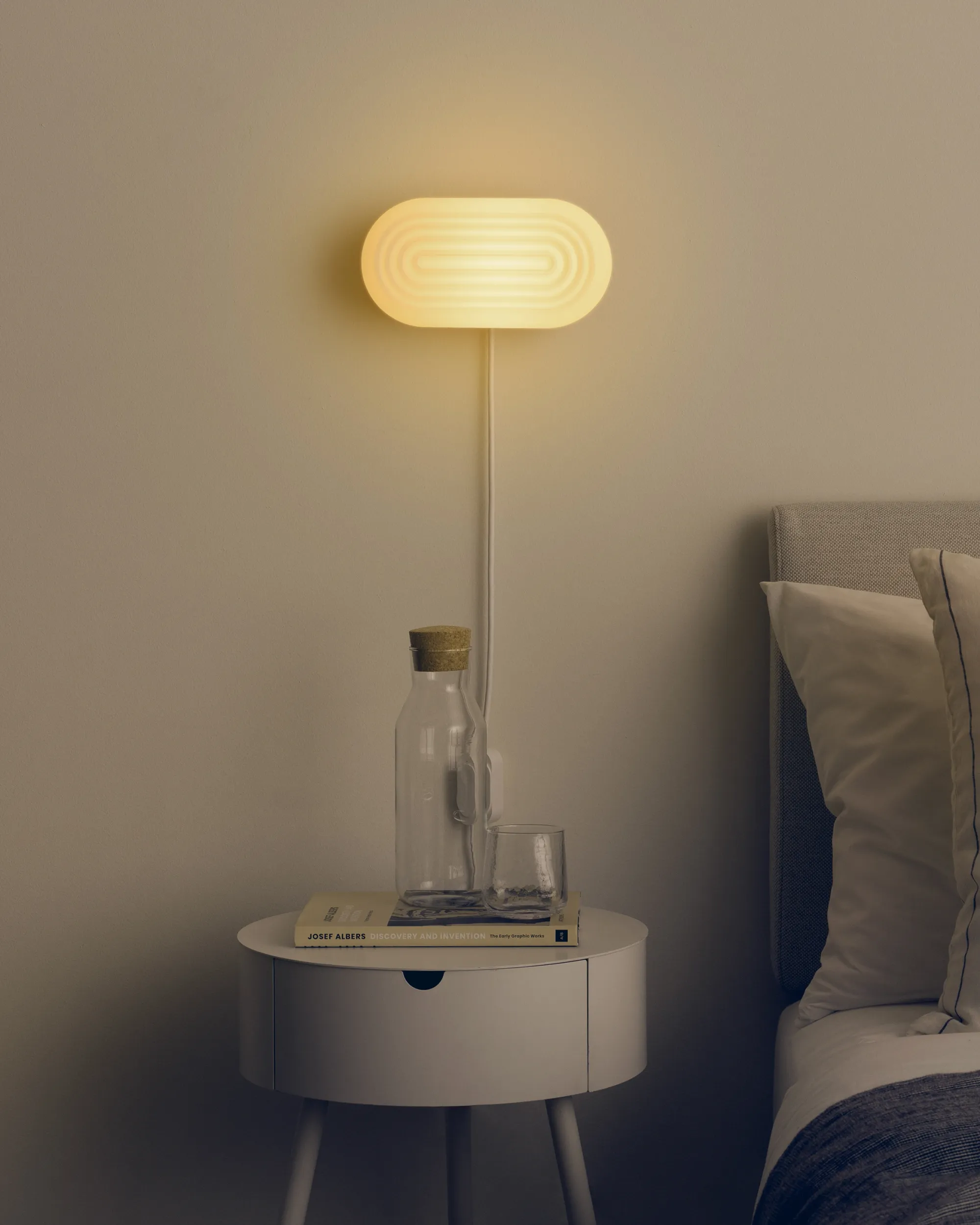 Gantri’s Focal Wall Light hangs above a bedside table and illuminates the space