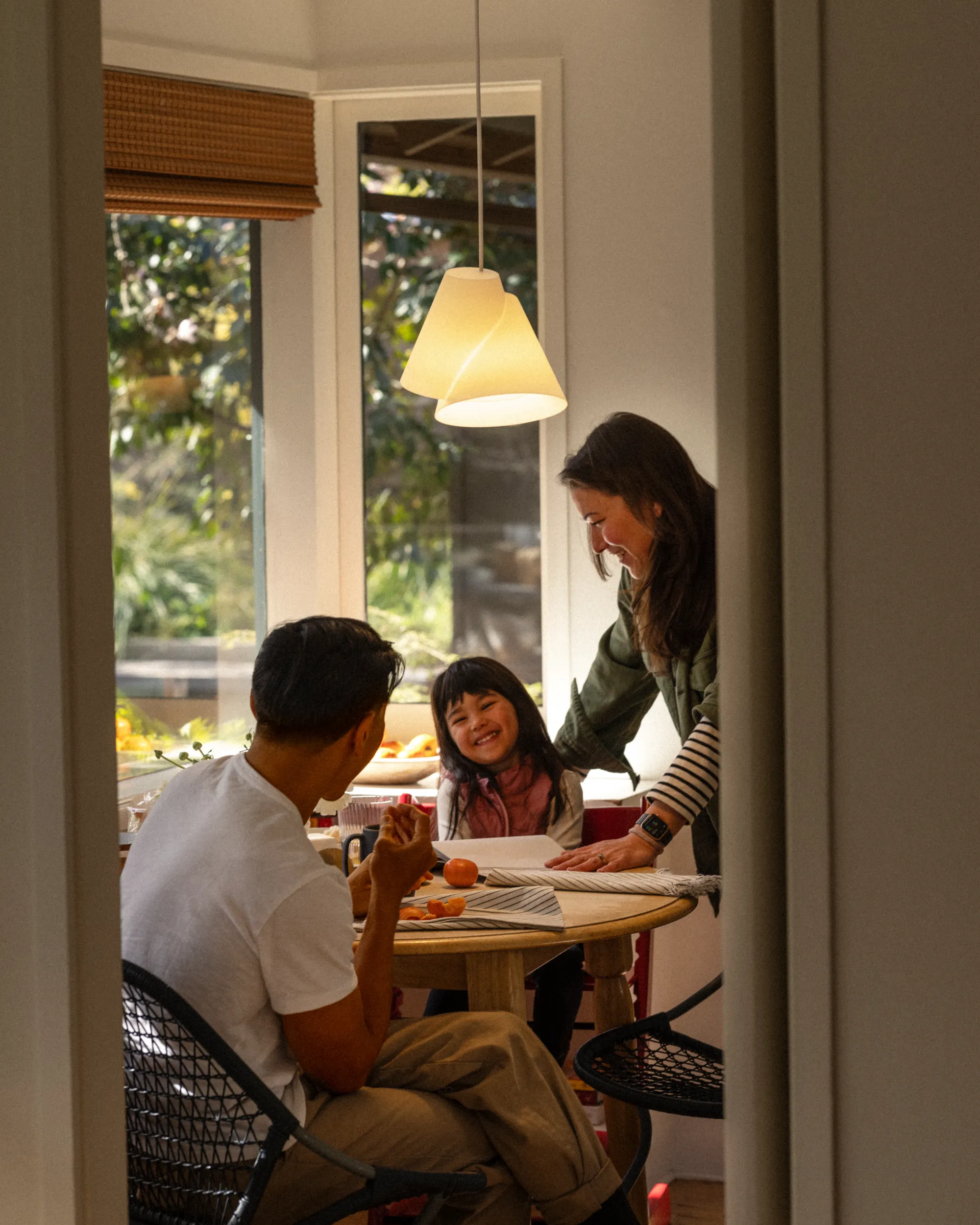 A family of three sharing a moment on their kitchen table with a Gantri Croissant Pendant Light illuminating their dining table