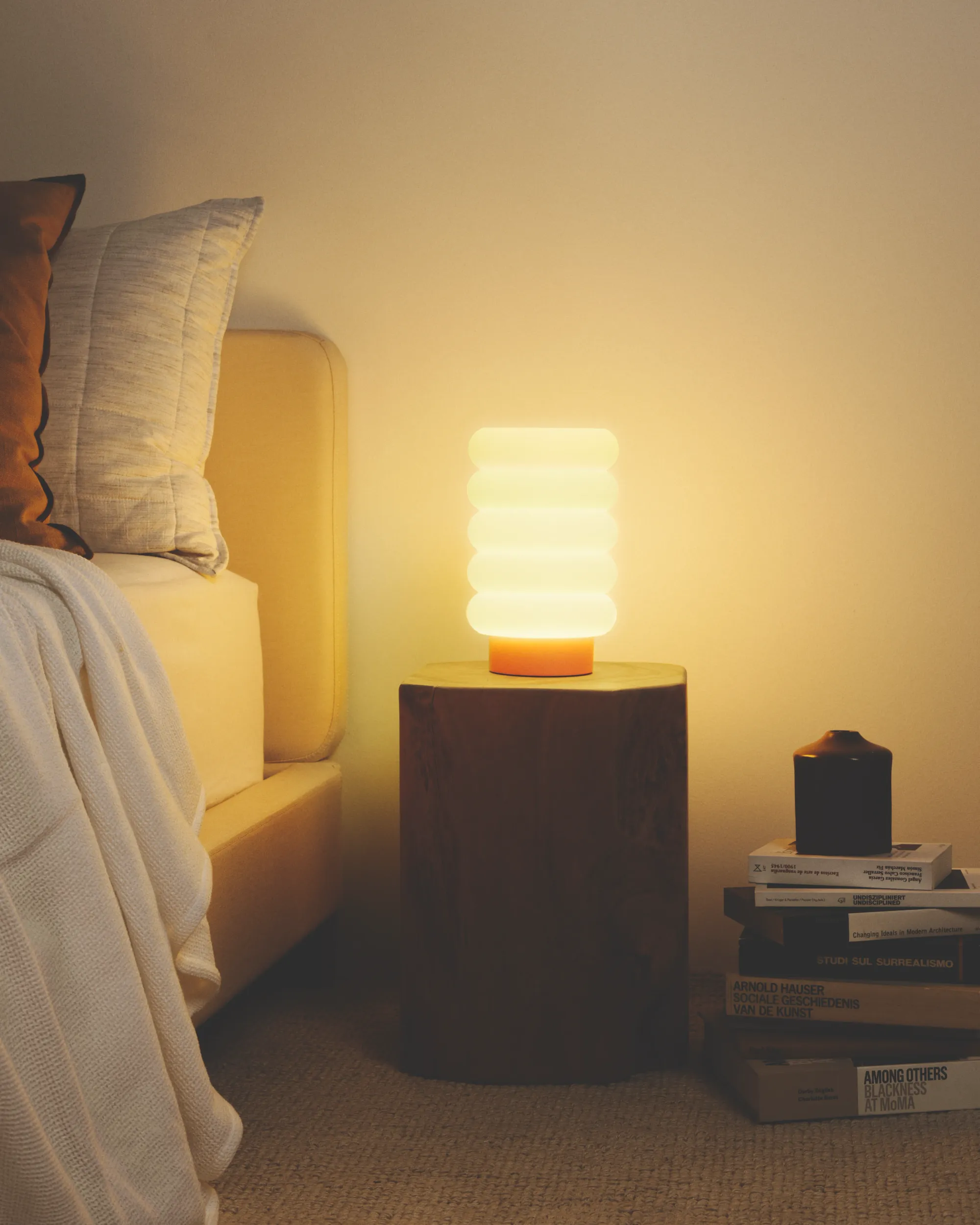 A bed with white sheets illuminated by light from a Gantri Argizari light