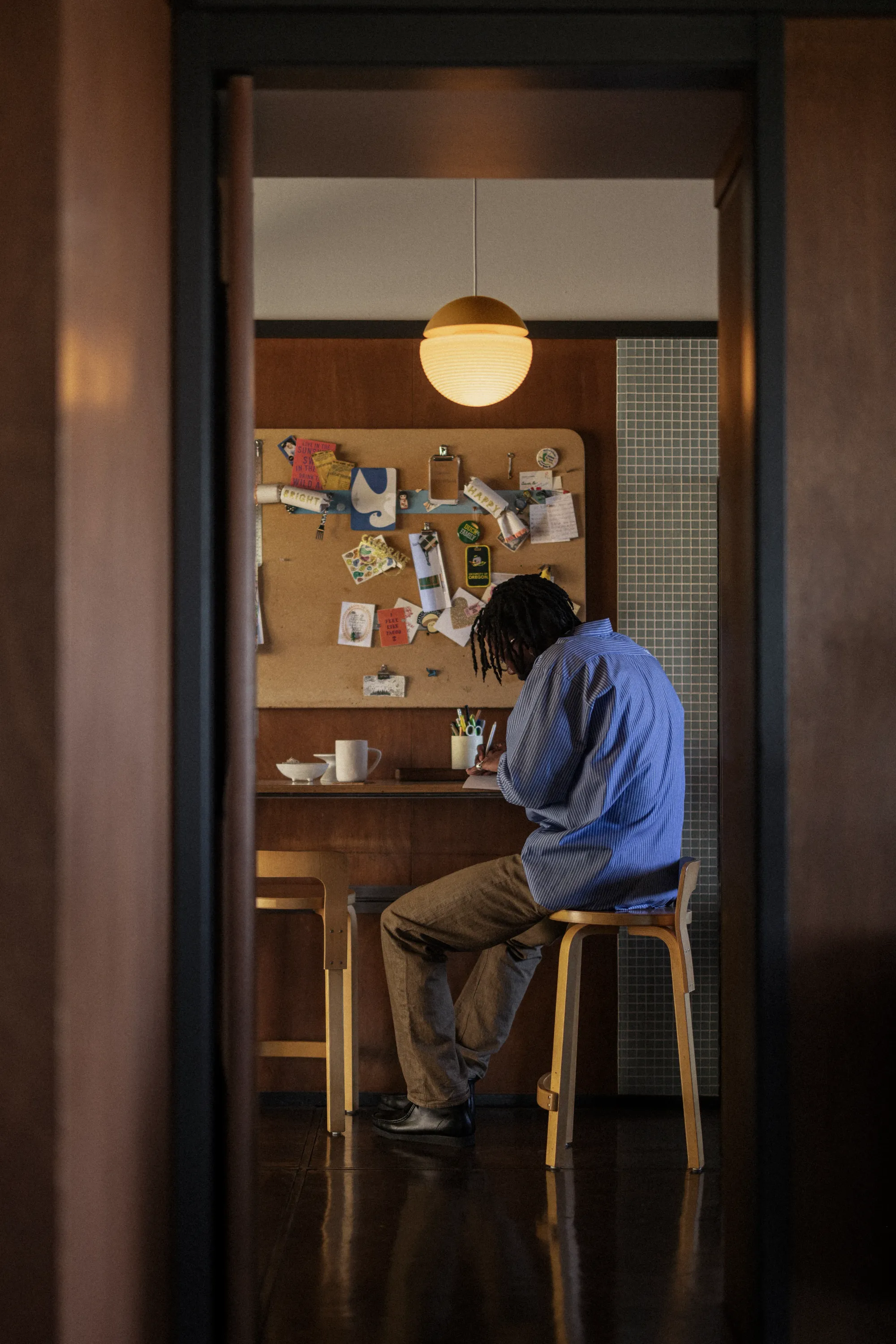 A man working on his kitchen table slash work area illuminated by the Gantri Cora Pendant Light