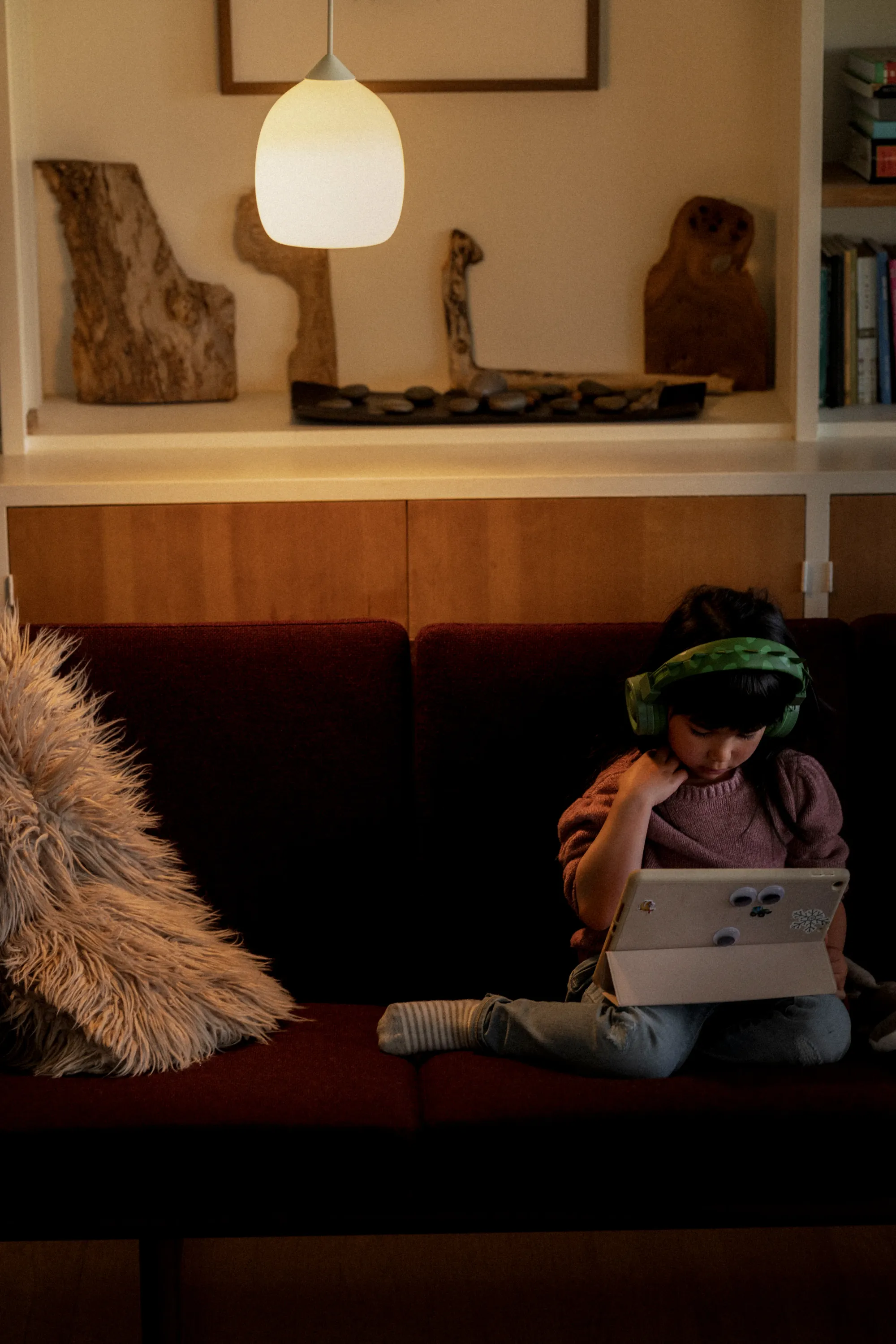 A child sitting on their living room couch illuminated by a Gantri Gulp pendant light