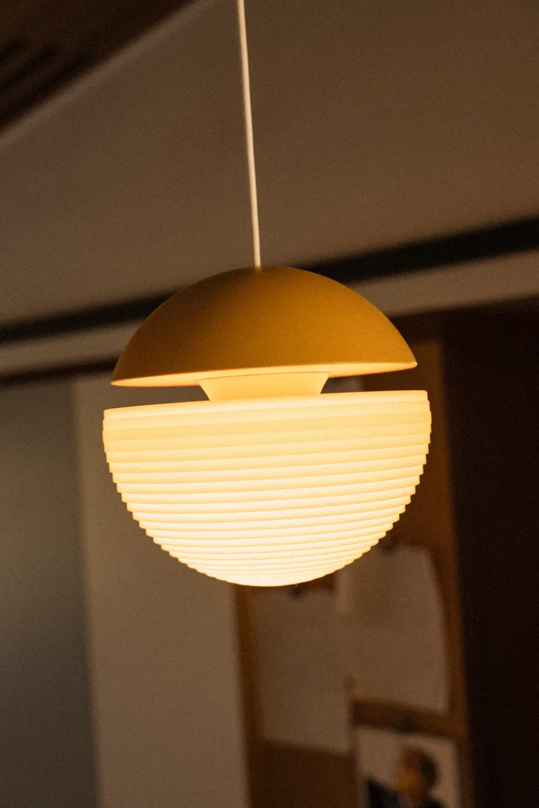 A Gantri Cora Pendant Light lit up and in focus