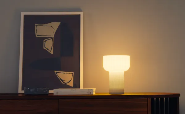 A desk lamp designed by Gantri perched on a living room dresser lighting the room. 